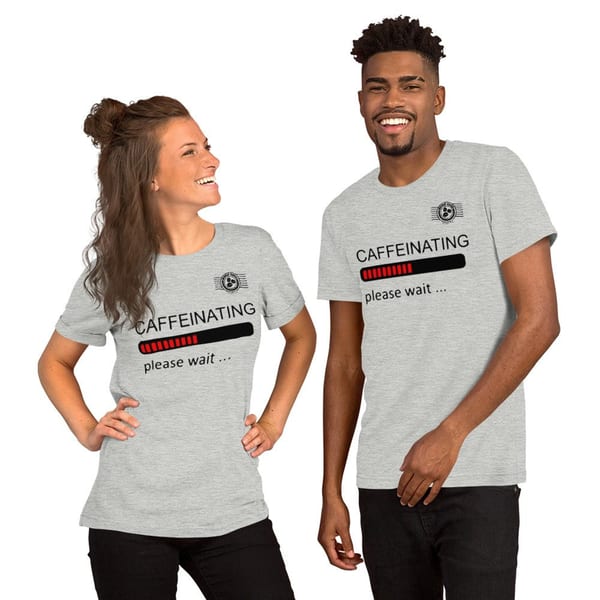 A smiling man and woman wearing matching grey World Blend Coffee "Caffeinating" t-shirts.