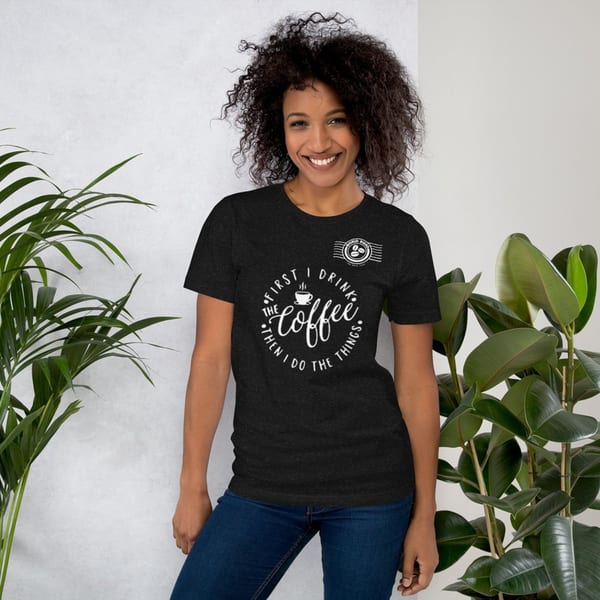 Smiling woman in a black World Blend Coffee t-shirt with "First I Drink The Coffee Then I Do The Things" text.
