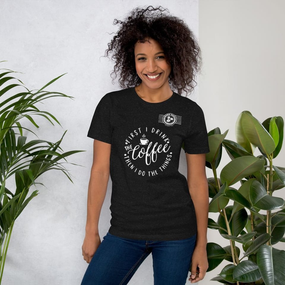 Smiling woman in a black World Blend Coffee t-shirt with "First I Drink The Coffee Then I Do The Things" text.